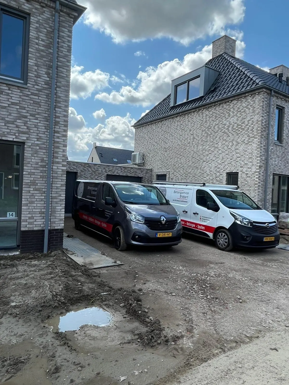 Twee bedrijfsbussen van Behangservice Brabant bij een woning