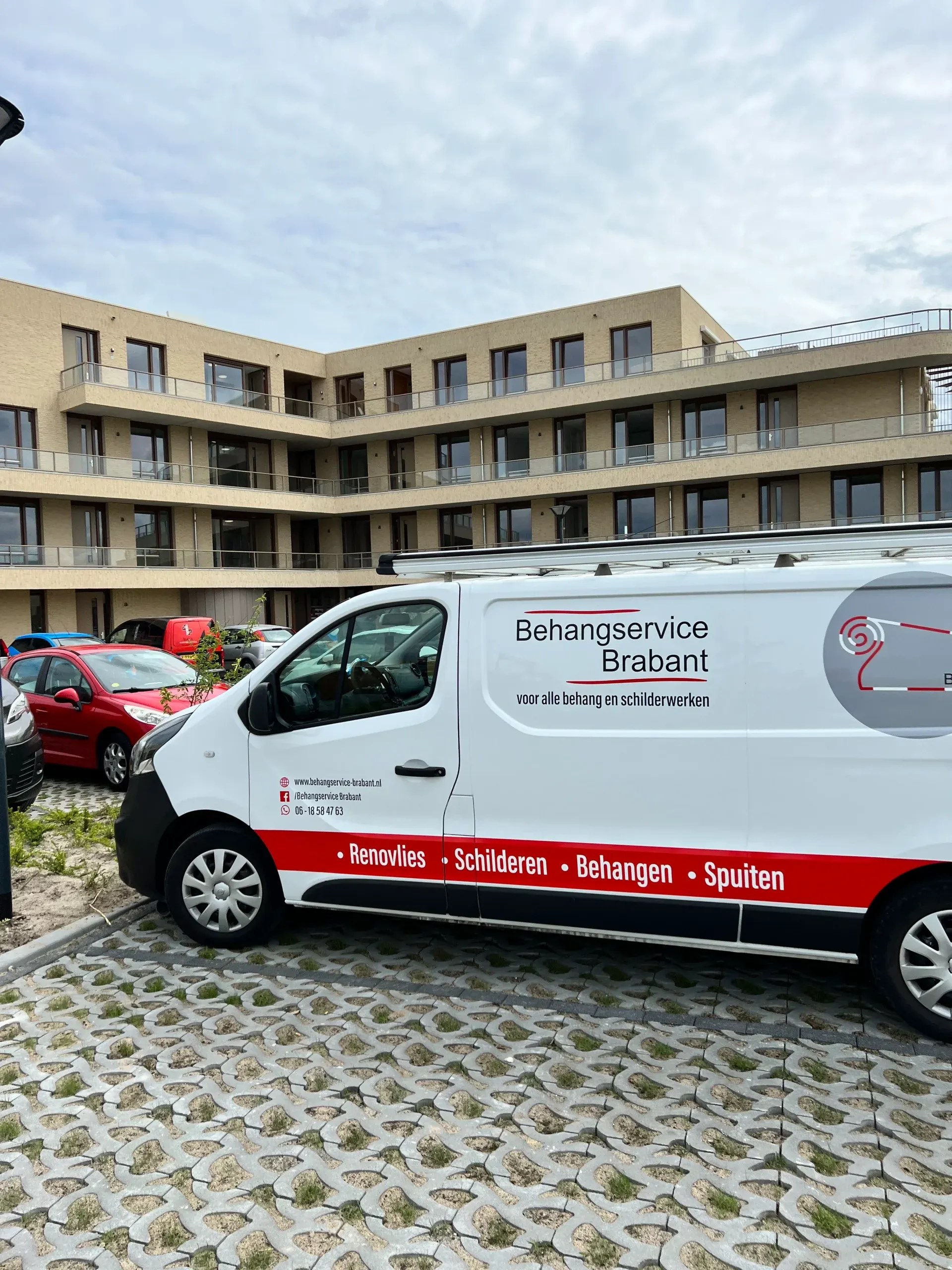 Bedrijfsbus van Behangservice Brabant bij een appartementencomplex